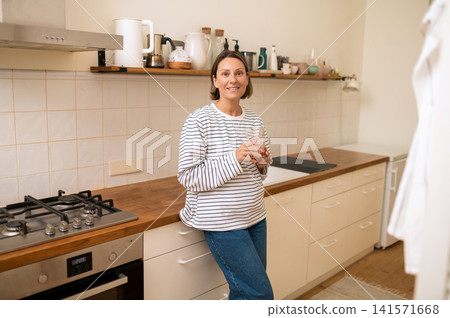 Portrait of smiling middle aged woman with glass of water Portrait of smiling middle aged woman with glass of water 141571668