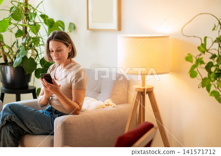 Concentrated middle aged woman typing message on phone Concentrated middle aged woman typing message on phone 141571712