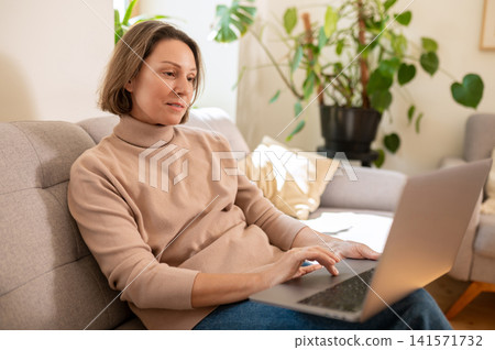 Middle aged female freelancer working on laptop Middle aged female freelancer working on laptop 141571732