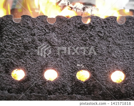 Dark surface of the grill with fire in the holes Dark surface of the grill with fire in the holes 141571818
