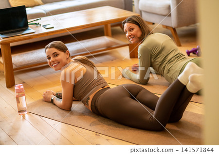 Smiling women resting in half plank pose on floor Smiling women resting in half plank pose on floor 141571844