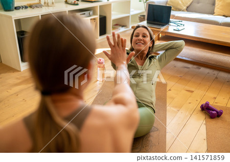 Happy middle-aged female exercising with instructor Happy middle-aged female exercising with instructor 141571859