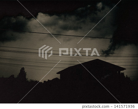Dark silhouette of a house beneath dramatic storm clouds. Atmospheric suburban landscape with moody sky, approaching thunderstorm. Rural cottage house Dark silhouette of a house beneath dramatic storm clouds. Atmospheric suburban landscape with moody sky, approaching thunderstorm. Rural cottage house 141571936