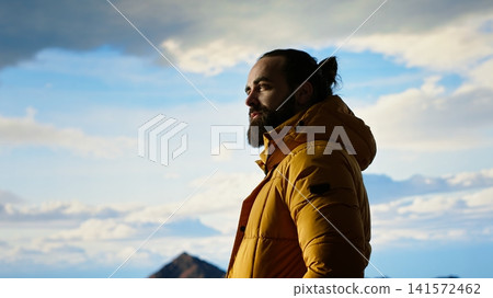 Hiker embraces the challenge of trekking through the wilderness, enjoys panoramic mountain landscape as a reminder of strength and the rewards of outdoor adventure. Adventure seeker. Camera B. Hiker embraces the challenge of trekking through the wilderness, enjoys panoramic mountain landscape as a reminder of strength and the rewards of outdoor adventure. Adventure seeker. Camera B. 141572462