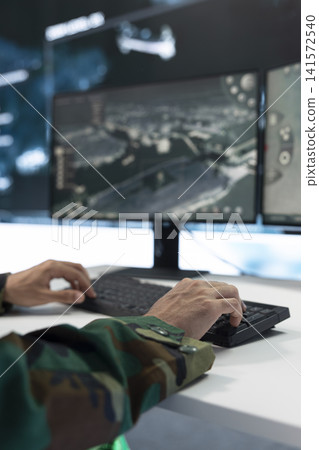 Close up of military personnel using surveillance software, typing on PC keyboard in command center. Army tactical analyst updates target data and defensive operation coordinates on computer Close up of military personnel using surveillance software, typing on PC keyboard in command center. Army tactical analyst updates target data and defensive operation coordinates on computer 141572540