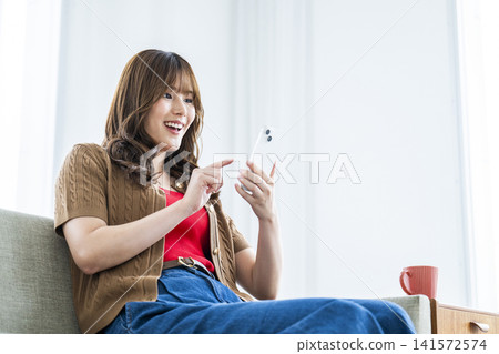 一個操作智能手機的年輕女子 一個操作智能手機的年輕女子 141572574