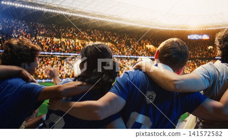 Back view of football supporters in stadium stands doing choreography, creating passionate atmosphere. Group of people swaying from side to side in soccer arena, enjoying match 141572582