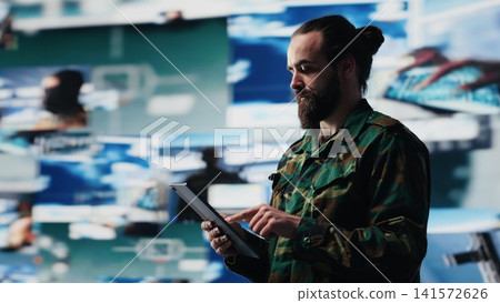 Military officer engaged in tactical command and surveillance activity integrating data, intelligence and AI warfare systems for battlefield efficiency in a national defense mission. Camera A. Military officer engaged in tactical command and surveillance activity integrating data, intelligence and AI warfare systems for battlefield efficiency in a national defense mission. Camera A. 141572626