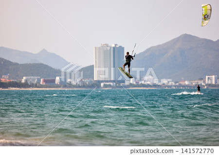Extreme Kitesurfing Jump with Coastal Mountains in Background Extreme Kitesurfing Jump with Coastal Mountains in Background 141572770