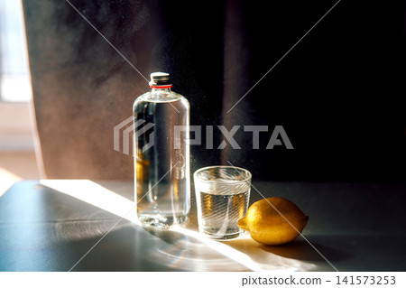 Refreshing water in glass and bottle with lemon Refreshing water in glass and bottle with lemon 141573253
