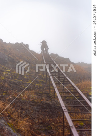 Silhouette of a climber ascending a long iron ladder (Genji Ladder) near Gongen-dake in the Yatsugatake Mountains. Silhouette of a climber ascending a long iron ladder (Genji Ladder) near Gongen-dake in the Yatsugatake Mountains. 141573614