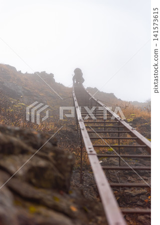 Silhouette of a climber ascending a long iron ladder (Genji Ladder) near Gongen-dake in the Yatsugatake Mountains. Silhouette of a climber ascending a long iron ladder (Genji Ladder) near Gongen-dake in the Yatsugatake Mountains. 141573615