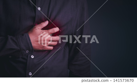 A grown man clutches his chest in agony during a severe heart attack, illustrating a critical cardiovascular and medical emergency. 141573670