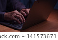 Close up of male hands typing on a laptop computer keyboard at night. Working late on modern business technology, internet connection, remote work, and online digital network communication. 141573671