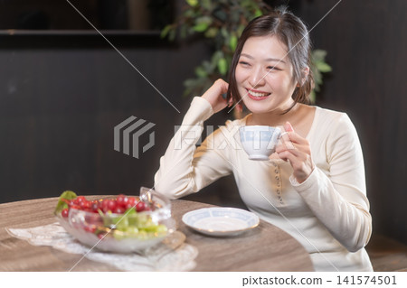 A young woman with a smile relaxing while drinking coffee. A young woman with a smile relaxing while drinking coffee. 141574501