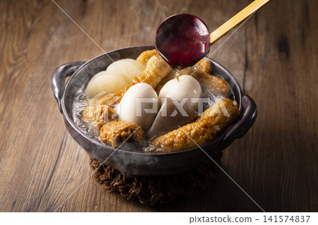 An image of someone pouring broth from an oden pot with a ladle. An image of someone pouring broth from an oden pot with a ladle. 141574837
