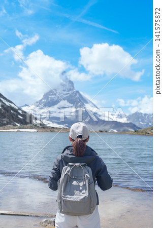 Woman Tourist Exploring Zermatt, Switzerland. happy hiker sightseeing iconic Matterhorn Swiss Alps at Riffelsee Lake, Famous European Landmark, Hiking Attraction and Travel Destination in Europe Woman Tourist Exploring Zermatt, Switzerland. happy hiker sightseeing iconic Matterhorn Swiss Alps at Riffelsee Lake, Famous European Landmark, Hiking Attraction and Travel Destination in Europe 141575872
