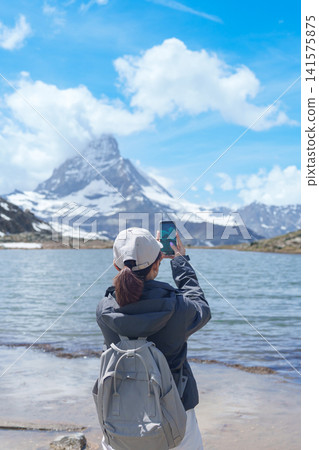 Woman Tourist Exploring Zermatt, Switzerland. Traveler Taking Photo with Smartphone at Riffelsee Lake and Iconic Matterhorn, Famous European Landmark, Hiking Attraction, Travel Destination in Europe 141575875