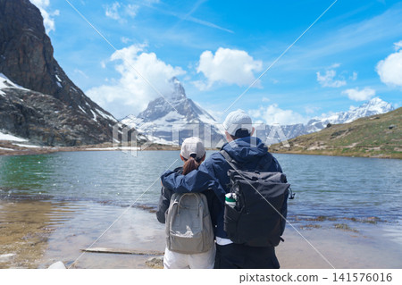 Couple Tourist Exploring Zermatt, Switzerland. happy hiker sightseeing iconic Matterhorn Swiss Alps at Riffelsee Lake, Famous European Landmark, Hiking Attraction and Travel Destination in Europe 141576016