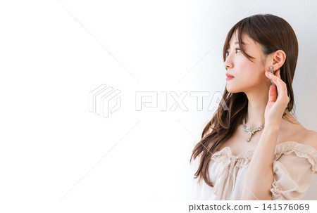 A young Asian woman in a dress, wearing a necklace and earrings. A young Asian woman in a dress, wearing a necklace and earrings. 141576069