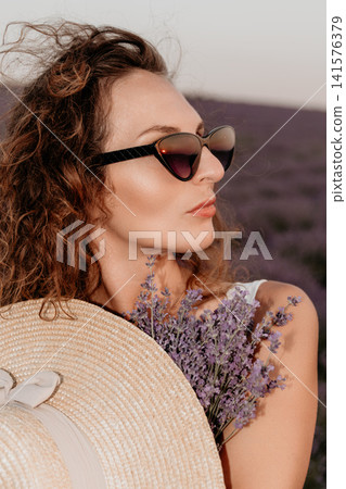 Woman lavender flower nature portrait of an elegant lady wearing a straw hat while standing in a blooming purple field Woman lavender flower nature portrait of an elegant lady wearing a straw hat while standing in a blooming purple field 141576379