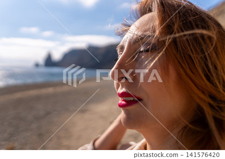 Woman beach serenity enjoying the sun and ocean breeze on a scenic coastline during a bright summer day 141576420