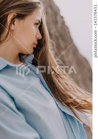 Woman portrait outdoor profile of a beautiful young lady with long hair wearing a blue shirt standing near a rock wall Woman portrait outdoor profile of a beautiful young lady with long hair wearing a blue shirt standing near a rock wall 141576431