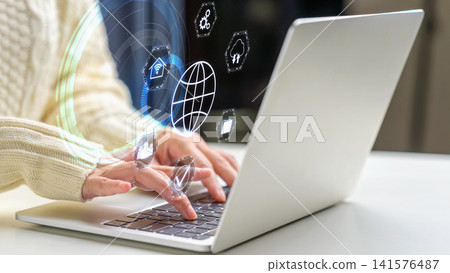 Close-up of hands typing on a laptop keyboard with abstract holographic icons representing internet connectivity, cloud computing, and digital technology. Concept of Remote working Close-up of hands typing on a laptop keyboard with abstract holographic icons representing internet connectivity, cloud computing, and digital technology. Concept of Remote working 141576487
