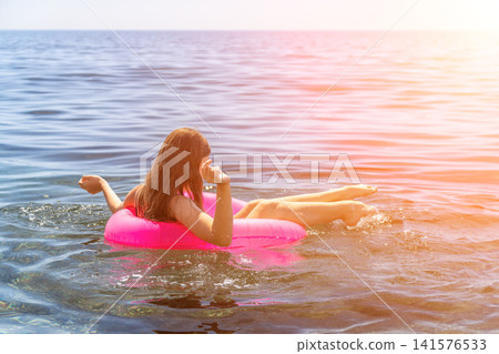 Young woman relaxing floating bright pink inflatable ring calm blue ocean water summer vacation travel copy space Young woman relaxing floating bright pink inflatable ring calm blue ocean water summer vacation travel copy space 141576533