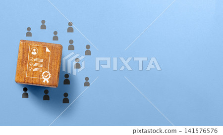 A wooden block with an icon of a resume and a badge on a blue background surrounded by silhouettes of people. Concept of Recruitment Qualification A wooden block with an icon of a resume and a badge on a blue background surrounded by silhouettes of people. Concept of Recruitment Qualification 141576576
