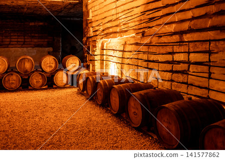 Wooden wine barrels stored in historic underground limestone cellars Wooden wine barrels stored in historic underground limestone cellars 141577862