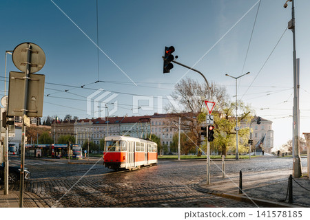 Historic Red Tram Crossing Cobblestone Streets at Sunrise in Prague Czech Republic Historic Red Tram Crossing Cobblestone Streets at Sunrise in Prague Czech Republic 141578185