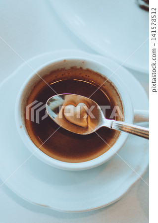 在咖啡杯裡放一些心形糖塊。 在咖啡杯裡放一些心形糖塊。 141578512