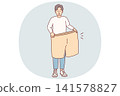 Lost weight man with big shorts in hands is surprised at size of own clothes from past 141578827