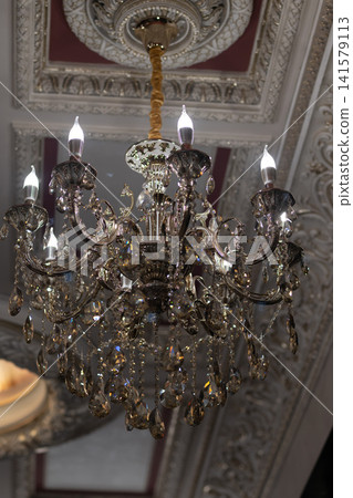 Luxury Crystal Chandelier with Ornate Ceiling Moldings in Elegant Vintage Interior. Luxury Crystal Chandelier with Ornate Ceiling Moldings in Elegant Vintage Interior. 141579113