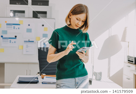 Closeup image of a businesswoman using mobile phone in office Closeup image of a businesswoman using mobile phone in office 141579509