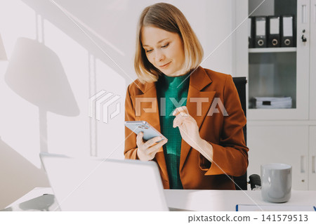 Woman smiling to herself as she works in an office Woman smiling to herself as she works in an office 141579513