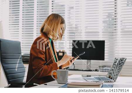 Woman smiling to herself as she works in an office Woman smiling to herself as she works in an office 141579514