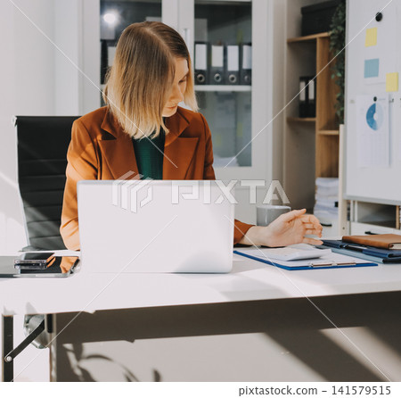 Woman smiling to herself as she works in an office Woman smiling to herself as she works in an office 141579515
