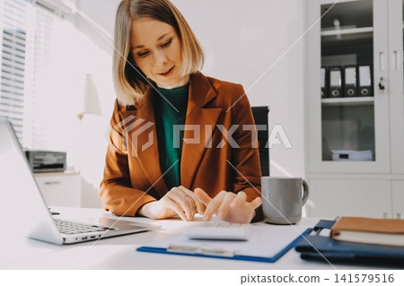 Woman smiling to herself as she works in an office Woman smiling to herself as she works in an office 141579516