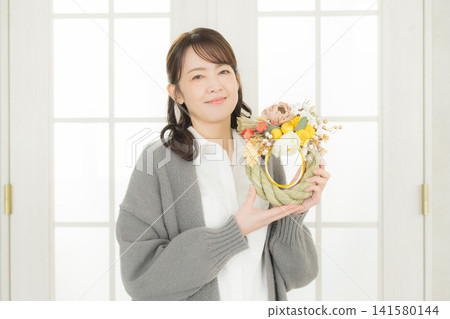 一位微笑的女子手捧注連繩花環。 一位微笑的女子手捧注連繩花環。 141580144