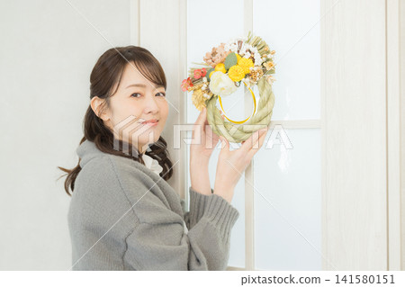 一位微笑的女子手捧注連繩花環。 一位微笑的女子手捧注連繩花環。 141580151