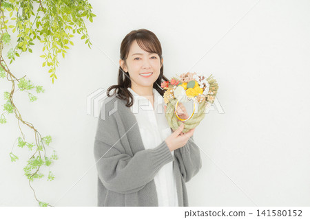 一位微笑的女子手捧注連繩花環。 一位微笑的女子手捧注連繩花環。 141580152