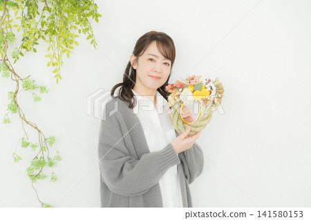 一位微笑的女子手捧注連繩花環。 一位微笑的女子手捧注連繩花環。 141580153