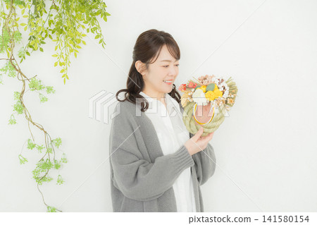 一位微笑的女子手捧注連繩花環。 一位微笑的女子手捧注連繩花環。 141580154