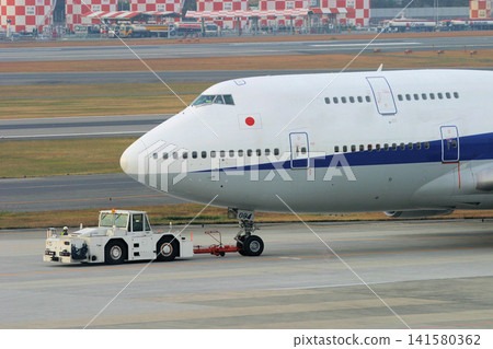 A B747 being towed by a towing vehicle. A B747 being towed by a towing vehicle. 141580362