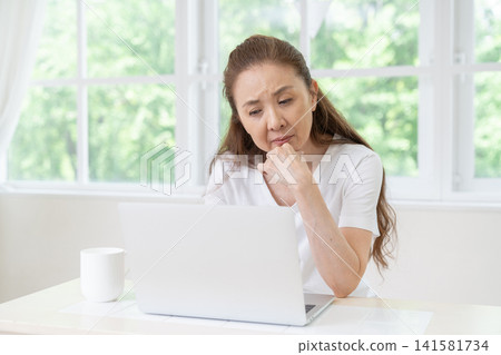 Senior women think about using computers. Senior women think about using computers. 141581734