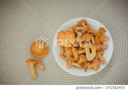 Flat lay of fresh raw chanterelle mushrooms on woven mat background. Flat lay of fresh raw chanterelle mushrooms on woven mat background. 141582455