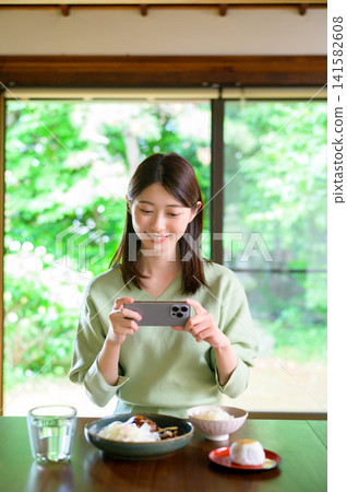 Japanese woman taking a photo of her meal with her smartphone Japanese woman taking a photo of her meal with her smartphone 141582608