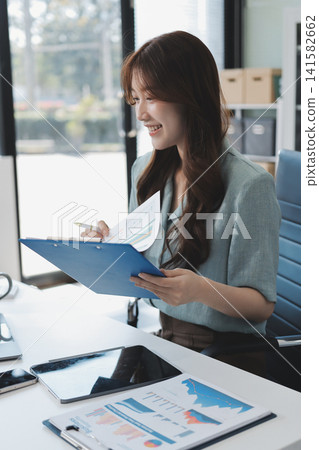 Businesswoman working with tablet and financial reports in modern office Businesswoman working with tablet and financial reports in modern office 141582662